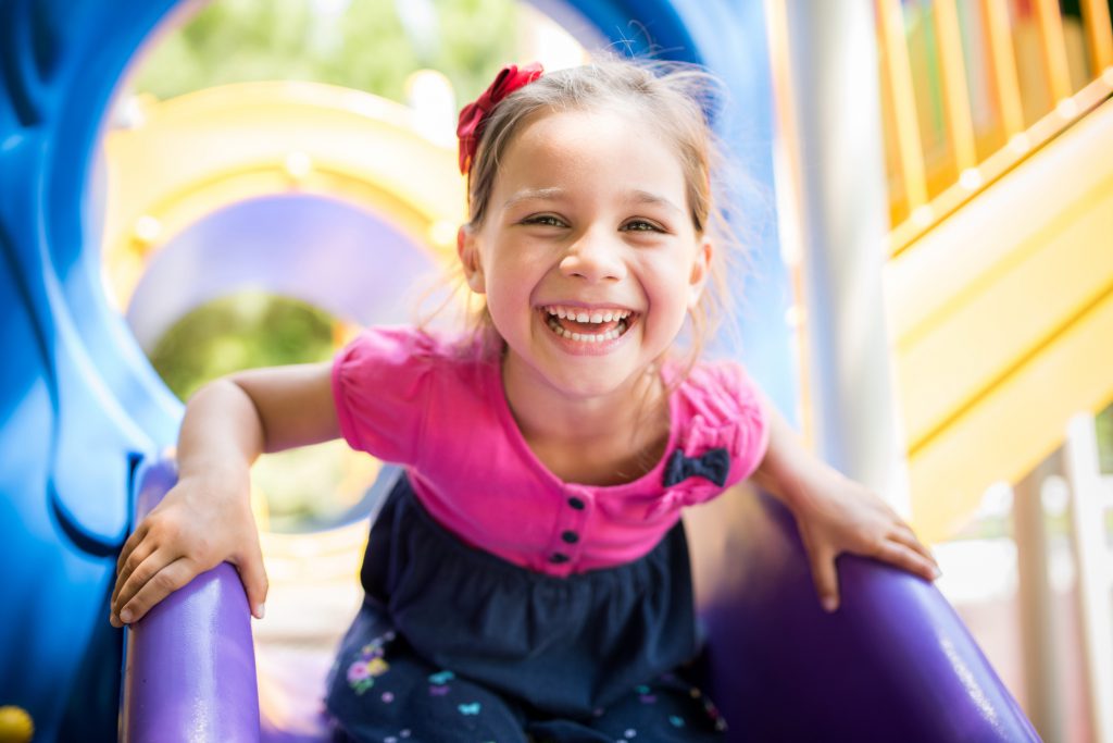 Little Girl Playing At Playground Outdoors In Summer