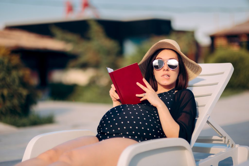 Mother to be keeping a pregnancy journal relaxing outdoors