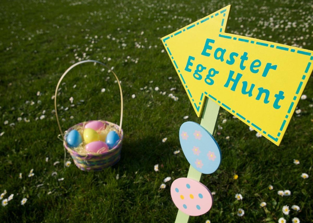 a sign that say egg hunt with it pointing toward lawn and eggs in a basket