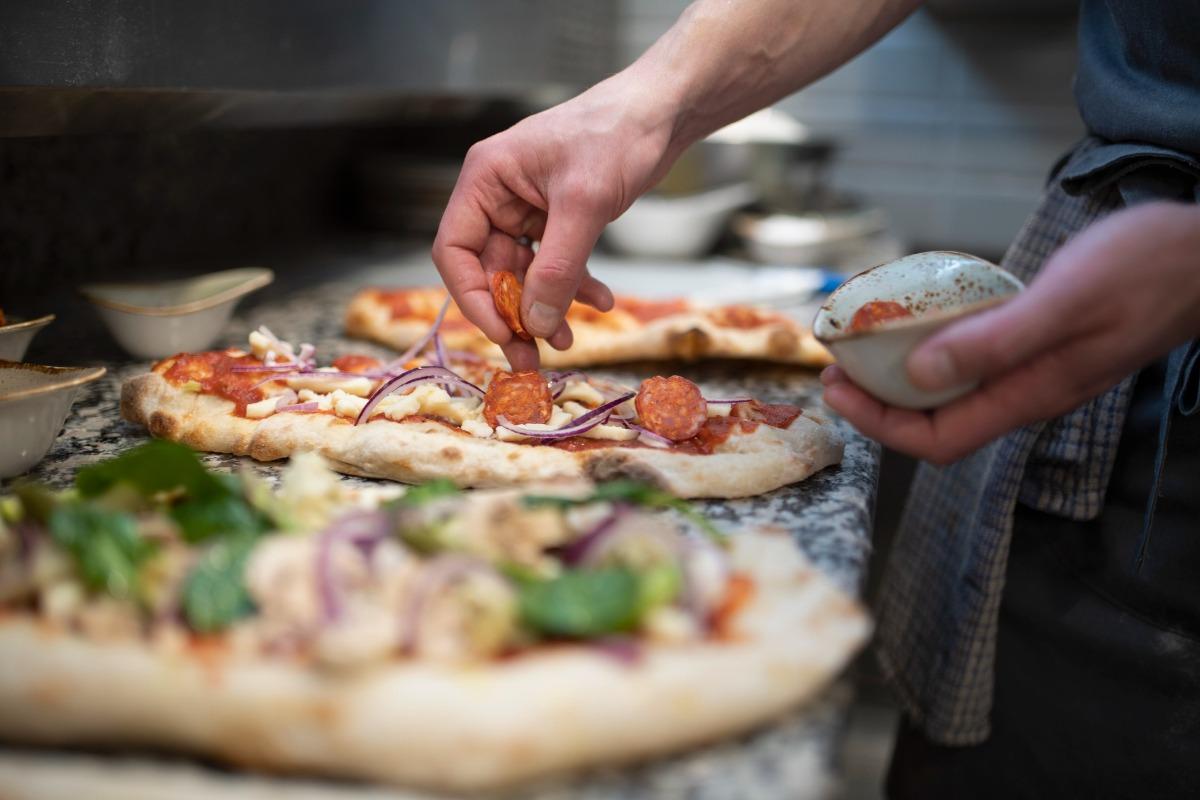 cheft at an Italian Restaurant fixing pizza to go into the wood-fired Oven